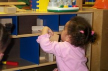 girl putting blocks on shelf